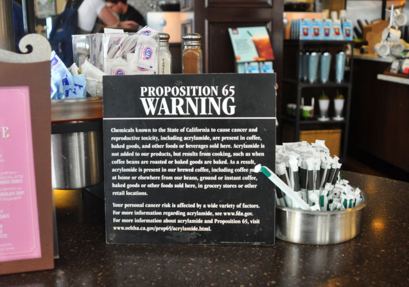 A black-and-white warning sign sits next to straws on a counter.