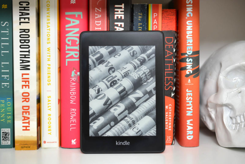 The 2018 Kindle Paperwhite leaning against a shelf of books.