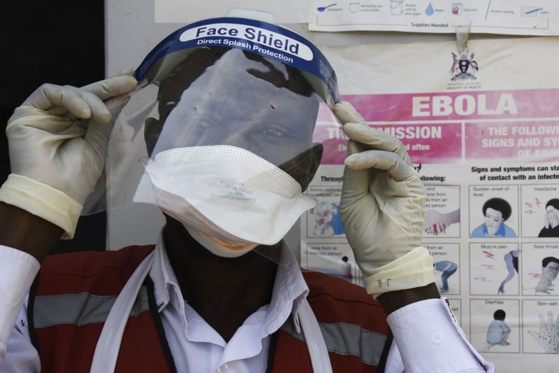 A health worker puts on protective gear as he prepares to screen travelers at the Mpondwe Health Screening Facility in the Ugandan border town of Mpondwe as they cross over from the Democratic Republic of Congo, on June 13, 2019. 