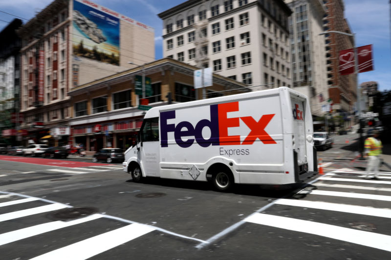A FedEx delivery vehicle drives through a city street.