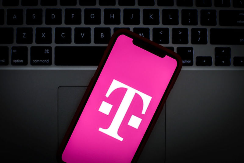T-Mobile's logo on the screen of a smartphone that's laying on top of a laptop keyboard.