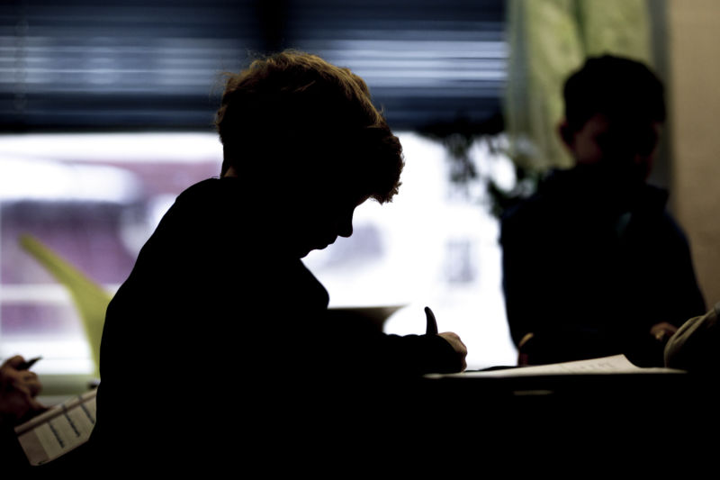 Stylized photograph of a boy writing at a desk.