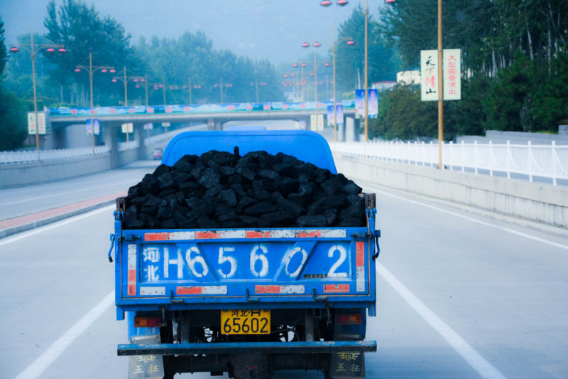 A truck filled with coal drives down a freeway in China.