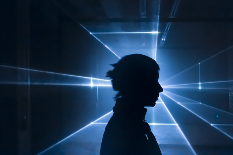 Silhouette of woman in front of laser-light projection.
