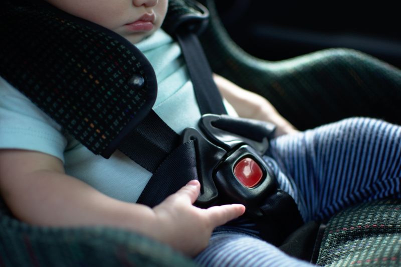 Photograph of a baby locked into a car seat.