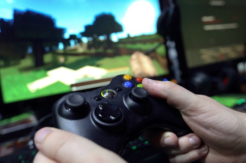 A visitor holds a hand control unit to play Minecraft during the EGX gaming conference in London, September 2014.